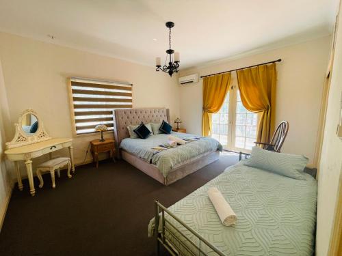a bedroom with two beds and a desk and a mirror at Villa Provence Estate in Pokolbin