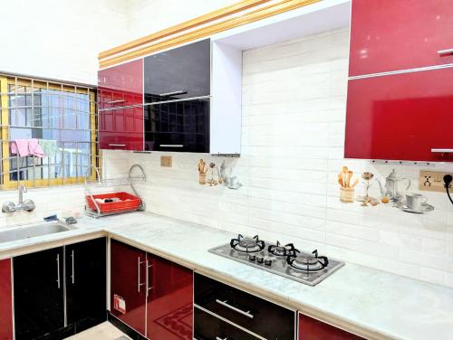 a kitchen with red cabinets and a stove top oven at House No 6, Valley Homes in Pothi