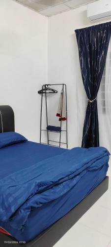 a bed with a blue comforter in a room at Homestay Rumah 311 in Sungai Petani