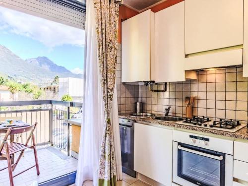a kitchen with white cabinets and a balcony with a table at Apartment Francesca by Interhome in Porlezza