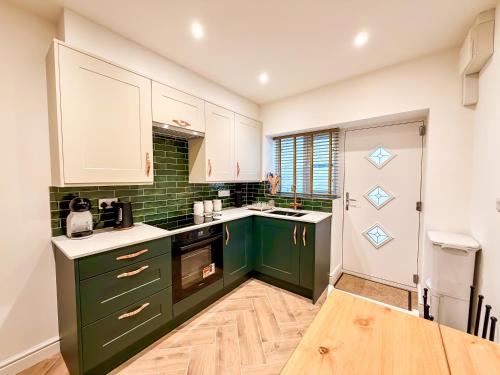 a kitchen with green cabinets and white counters at Broadweavers - Very Cute Cottage In Dursley By STAE-Homes in Gloucestershire