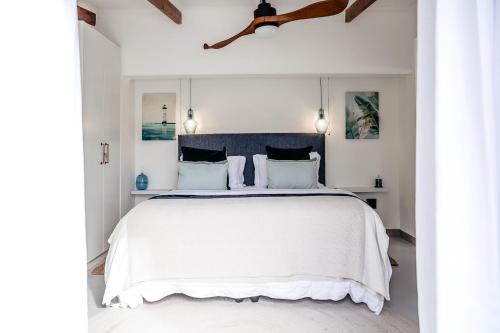 a bedroom with a white bed with a blue headboard at Lagoon Haven House in Hermanus