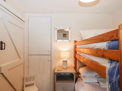 a bedroom with a bunk bed and a table with a lamp at Yew Tree Cottage in Dartmouth