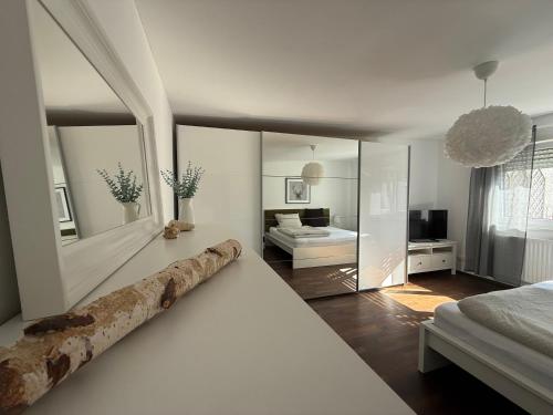 a white bedroom with a bed and a mirror at WEIDEN51 - Apartment für Business & Familien in Fürstenfeldbruck