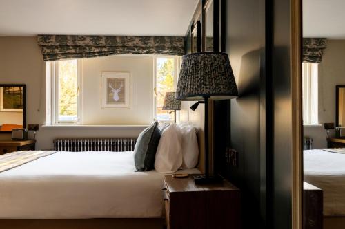 a bedroom with two beds and a lamp and a window at The White Hart in Stockbridge
