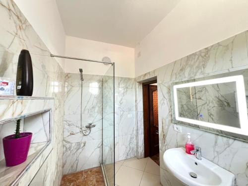 a bathroom with a glass shower and a sink at ES Berat Apartments in Berat