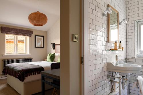 a bathroom with a bed and a sink and a mirror at The White Hart in Stockbridge