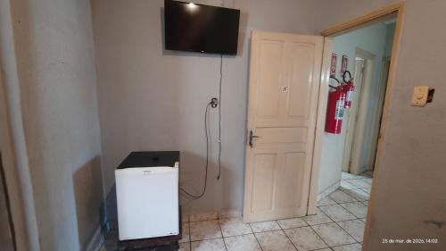 a room with a small refrigerator and a television on the wall at Pousada Itararé in São Vicente
