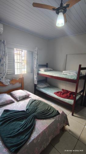 a room with three bunk beds and a ceiling fan at Pousada Itararé in São Vicente