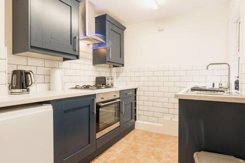 a kitchen with blue cabinets and white appliances at Stylish 3 bed home in central Chester suburb in Chester