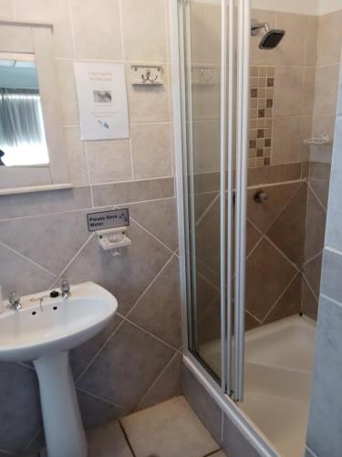 a bathroom with a shower and a sink at Aquarius Guesthouse in Jeffreys Bay