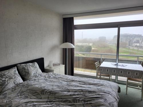 a bedroom with a bed and a large window at Studio Residentie Astrid Bredene in Bredene