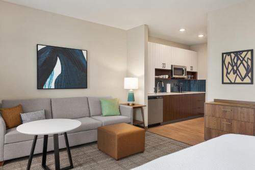 a living room with a couch and a table and a kitchen at Staybridge Suites Rockford by IHG in Rockford