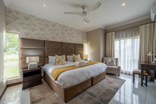 a bedroom with a large bed and a chair at The House in Hazyview