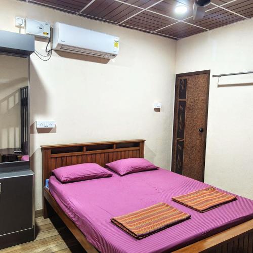 a bedroom with a purple bed with two towels on it at Adiga's Homestay Dharmasthala in Dharmastala