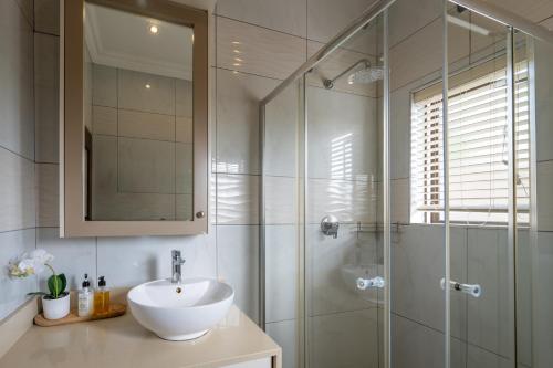 a bathroom with a sink and a glass shower at The House in Hazyview