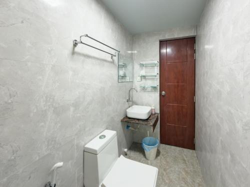 a white bathroom with a toilet and a sink at Diamond Stay Inn in Dhangethi