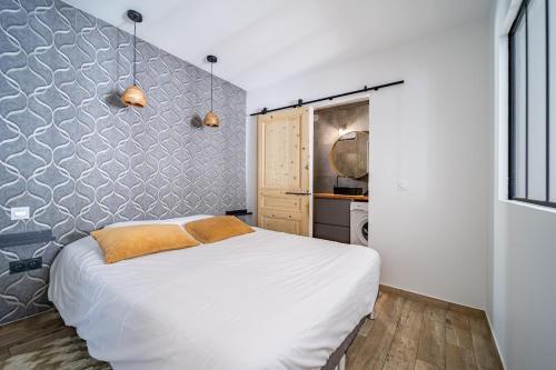 a bedroom with a white bed and a wall at L'Expresso in Frontonas