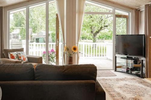a living room with a couch and a flat screen tv at Cosy Lodge on Farm with Donkeys Parking in Chester