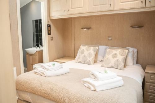 a bedroom with a bed with towels on it at Cosy Lodge on Farm with Donkeys Parking in Chester