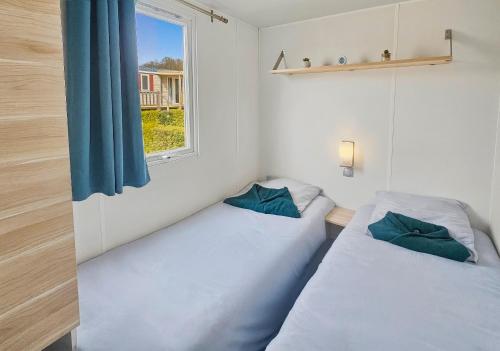 two beds in a small room with a window at Mobilhome in Litteau