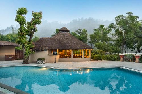 a resort with a swimming pool in front of a building at The Riverview Retreat Corbett by Leisure Hotels in Garjia