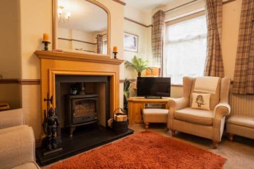 a living room with a fireplace and a chair and a television at Wirral Retreat Cosy Cottage Near Port Sunlight in Birkenhead