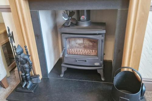 a wood stove in a living room with a statue at Wirral Retreat Cosy Cottage Near Port Sunlight in Birkenhead