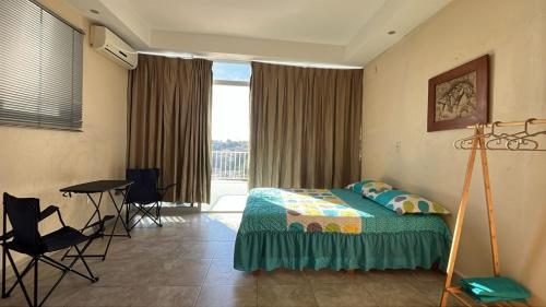 a bedroom with a bed and a table and a window at Casa Aca in Acapulco