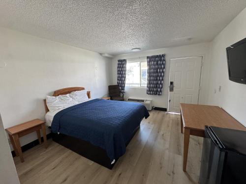 a bedroom with a bed and a desk and a television at Stallion Inn Motel in Long Beach