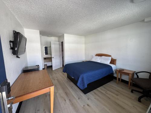 a small room with a bed and a television at Stallion Inn Motel in Long Beach