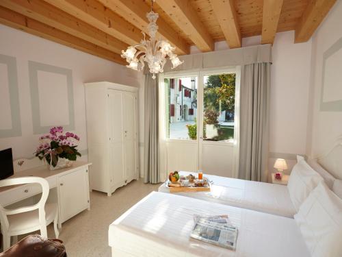 a room with a table and a desk and a window at Hotel Villa Patriarca - Buongiorno! Hotels in Mirano