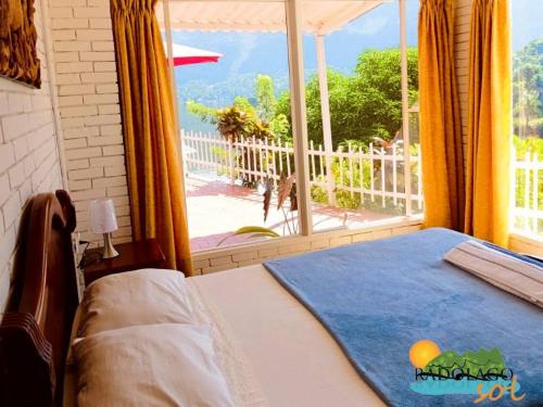 ein Schlafzimmer mit einem Bett und Blick auf einen Balkon in der Unterkunft Pradolago Sol Prado Tolima in Prado