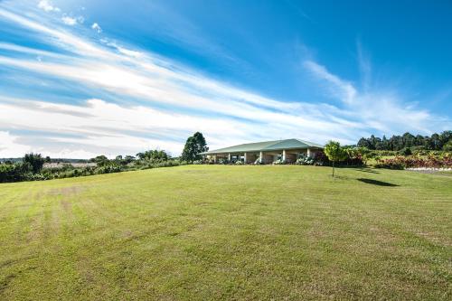 a large grass field with a house in the background at Mahana House Country Inn in North Hilo