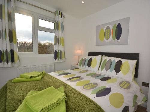 a bedroom with a bed with green sheets and a window at 3 Bed in Bridgwater oc-56284 in Greinton