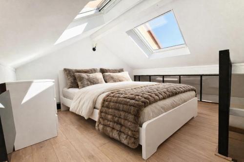 a white bedroom with a bed and a skylight at Ma Montagne Chic in La Bresse
