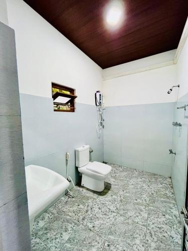 a bathroom with a toilet and a tub and a sink at Flourish holiday resort in Kataragama