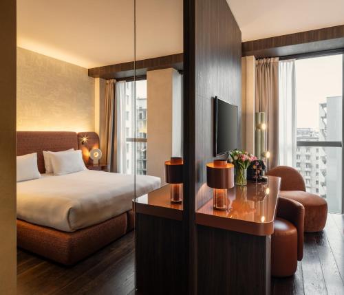 a hotel room with a bed and a tv and a couch at Hyatt Centric Milan Centrale in Milan