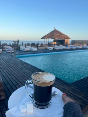 a cup of coffee on a table next to a pool at maison d'hôtes la merveille in Dakhla