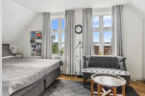 a bedroom with a bed and a chair and a clock at Det gamle Apotek Møn in Stege