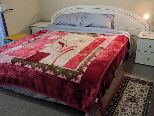 a bedroom with a bed with a red blanket at BIDWILL GARDENS ON MIDDLETON - 2 Rooms A Private Room with a King-Size Bed or Open Lounge Room Floor Mattress SHARED Bathroom FREE Kitchen Essentials FREE Laundry Facilities Fast WIFI HDTV NETFLIX, YOUTUBE, KAYO Meal and Transport Services Available in Bidwill