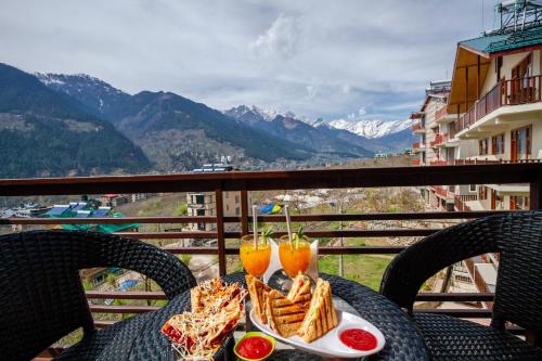 a table with food and two drinks on a balcony at Hotel SNAS Retreat Manali in Manāli