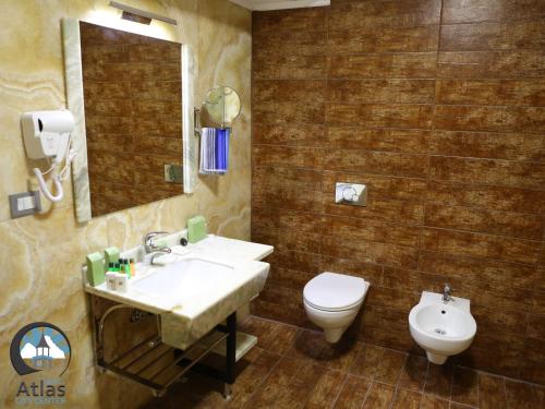 a bathroom with a sink and a toilet and a mirror at Atlas City Center Hotel in Prilep