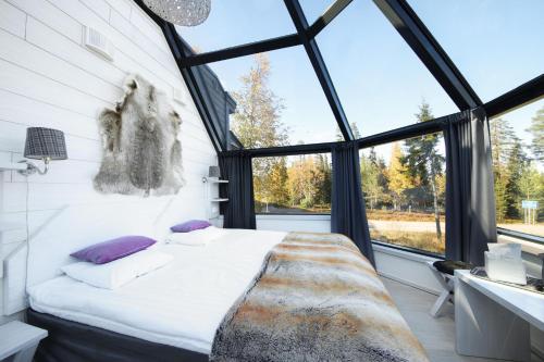 ein Schlafzimmer mit einem Bett in einem Zimmer mit Fenstern in der Unterkunft Santa's Hotel Aurora & Igloos in Luosto