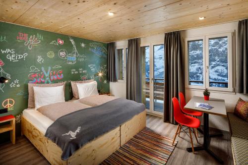 a bedroom with a bed and a desk and a wall with graffiti at Eiger Guesthouse in Mürren