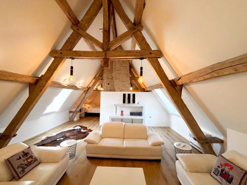 a living room with white furniture and wooden ceilings at Château de Foussal in Issigeac