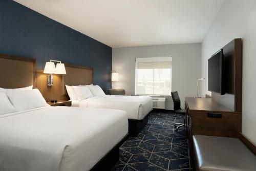 a hotel room with two beds and a flat screen tv at Hyatt Select St Louis Airport in Saint Louis