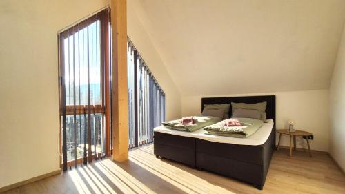 a bedroom with a bed and a large window at Haus am FELS, Alpenaster in Hermagor