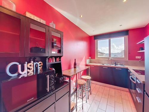 a kitchen with red walls and a counter with stools at Apartment U Centru by Interhome in Porto-Vecchio