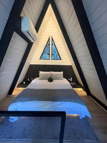 a large bed in a room with a window at Cabana Encanto A-FRAME Com Cachoeira in Bocaina de Minas